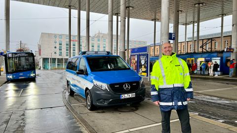 Ein Mann in gelber Sicherheitskleidung steht vor einem blauen Einsatzwagen der KVG. Im Hintergrund ist ein Bus und eine Straßenbahn zu sehen.