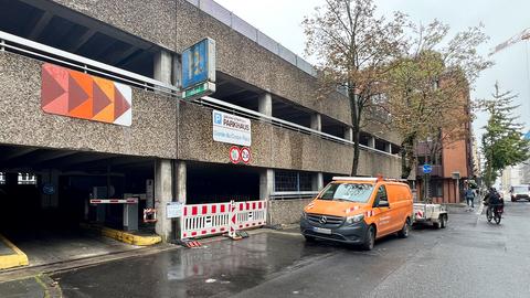 Altes Parkhausgebäude von außen. Unter dem Schild "Parkhaus" ist die Einfahrt mit rot-weißen Absperrgittern versperrt.