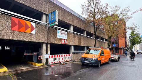 Altes Parkhausgebäude von außen. Unter dem Schild "Parkhaus" ist die Einfahrt mit rot-weißen Absperrgittern versperrt.