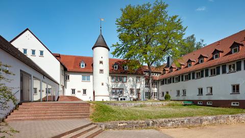 Ein weißes Gebäude umfasst einen grünen Innenhof. 