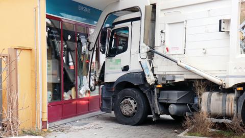 Ein Müllwagen steht vor einer beschädigten Schaufensterscheibe.