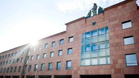 Schnörkelloses Gebäude von außen mit Justizia Figur am oberen Rand der Fassade.