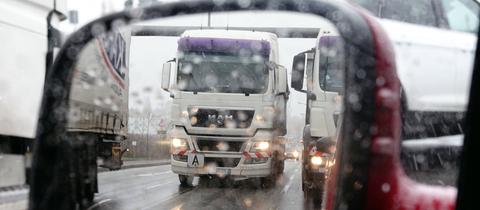 Lastwagen spiegeln sich auf regennasser Autobahn im Außenspiegel