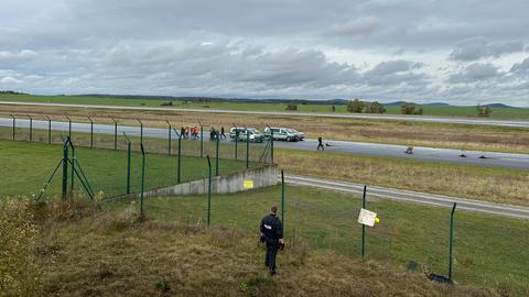 Blick auf die Bäume auf der Rollbahn in Calden (Kassel). Im Hintergrund stehen Polizeiautos.