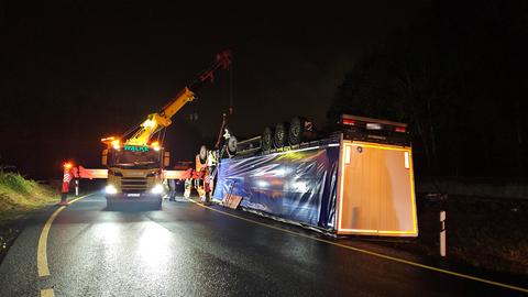 Lkw liegt komplett verkehrt herum auf Autobahn, daneben ein Kranwagen