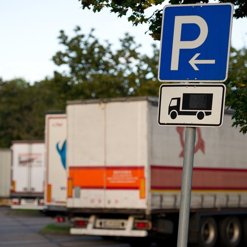 Geparkte Lastwagen stehen auf einem Autobahnrastplatz.