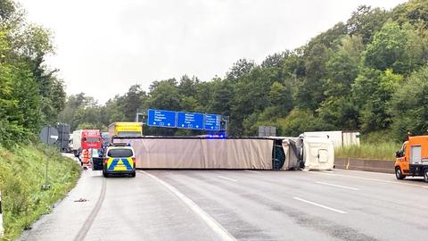 Autobahn mit einem sehr langen, umgefallenen LKW, der quer über die Fahrspuren liegt.