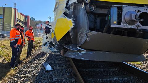 Arbeiter in Warnwesten stehen neben der beschädigten Regionalbahn.