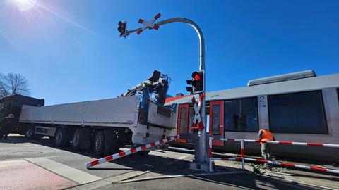 Arbeiter in Warnwesten stehen neben einer beschädigten Regionalbahn.