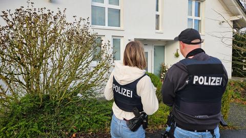 Zwei Polizeibeamte stehen vor einem weißen Wohnhaus in Löhnberg (Limburg-Weilburg)