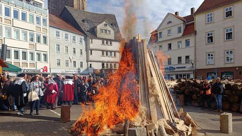 Feuer zum Beginn des Lullusfestes - aufgestapeltes Holz auf einem Platz in Bad Herfeld. Die Flammen züngeln. Menschen stehen drum herum.