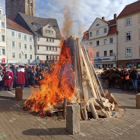 Feuer zum Beginn des Lullusfestes - aufgestapeltes Holz auf einem Platz in Bad Herfeld. Die Flammen züngeln. Menschen stehen drum herum.