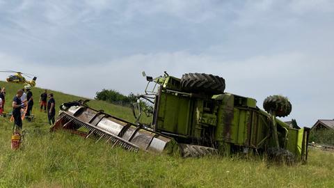 Ein Mähdrescher liegt seitlich auf einem Feld. 