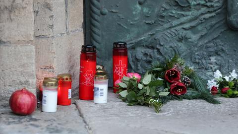 Das Bild zeigt aufgestellte Kerzen in roten und weißen Plastikdosen und niedergelegte rote Blumen in Magdeburg am Tag nach dem Anschlag auf den Weihnachtsmarkt. 