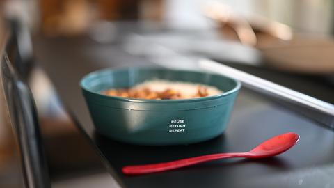 Eine Mehrwegschüssel steht mit Essen gefüllt auf einem Tisch.