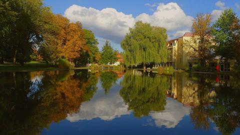 Bunt gefärbe Bäume und der blaue Himmel spiegeln sich in einem See.