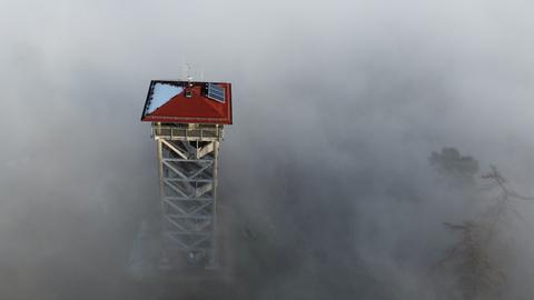 Ein begehbarer Turm ragt aus dem Nebel