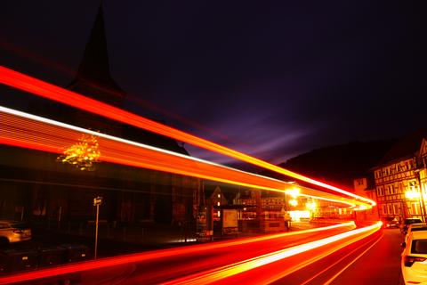 Langzeitbelichtung einer mit Weihnachtsbeleuchtung geschmückten Straße im nächtlichen Waldkappel, orange-roter Lichtstrahl auf Straße mit Fachwerkhäusern