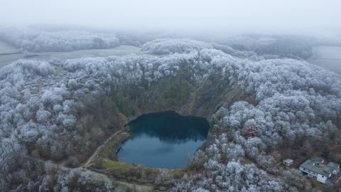 Eine Drohnenaufnahme: Der Steinbruch ist von oben zu sehen, leichter Schnee liegt auf dem Bäumen rundherum. 