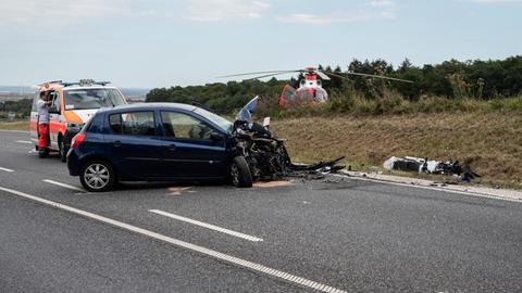 Motorrad liegt neben demoliertem Auto, Hubschrauber im Hintergrund