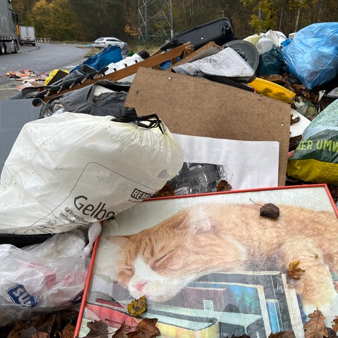 Riesige Haufen von Müll und vollgestopften Plastiktüten liegen auf einem Parkplatz.