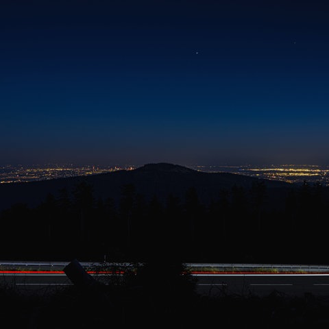 Blick in der Nacht vom Großen Feldberg im Taunus. Um den in Dunkelheit liegenden Altkönig herum sind die Lichter der Rhein-Main-Ebene und des Frankfurter Flughafens zu sehen.