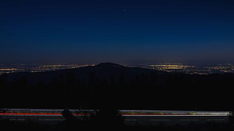 Blick in der Nacht vom Großen Feldberg im Taunus. Um den in Dunkelheit liegenden Altkönig herum sind die Lichter der Rhein-Main-Ebene und des Frankfurter Flughafens zu sehen.