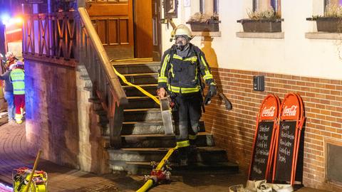 Feuerwehrmann mit Atemschutzmaske kommt Holztreppe von Gasthof herunter