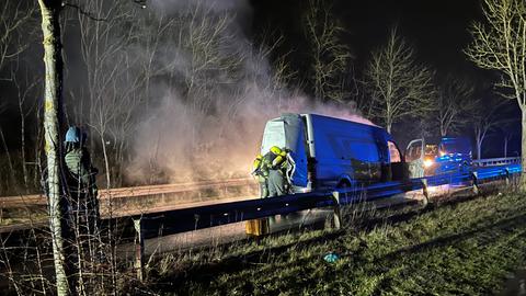 Transporter qualmt, Türen des Fahrzeugs sind geöffnet, drei Feuerwehrleute löschen