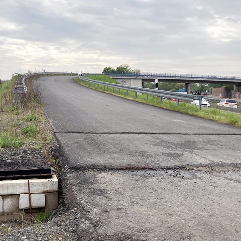 Foto einer Straße, die nach einer ansteigenden Kurve zu einer Brücke wird.