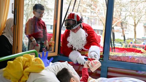 Ein als Nikolaus verkleideter Feuerwehrmann der Höhenrettungsgruppe der Hanauer Berufsfeuerwehr übergibt am Nikolaustag ein Geschenk an Kinder im Krankenhaus.