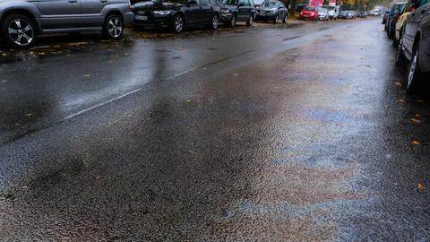 Ölspur auf Straße mit parkenden Autos.