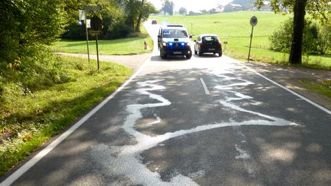 Das Symbolfoto zeigt eine Ölspur auf einer Straße im Landkreis Traunstein (Bayern). Ein Polizeiwagen sichert die Straße.