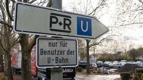 Schilder weisen auf einen Park-and-Ride-Parkplatz in Frankfurt hin. Im Hintergrund ist ein voller Parkplatz zu sehen.