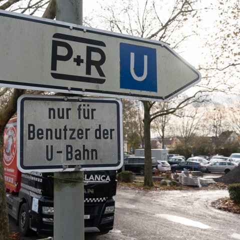 Schilder weisen auf einen Park-and-Ride-Parkplatz in Frankfurt hin. Im Hintergrund ist ein voller Parkplatz zu sehen.