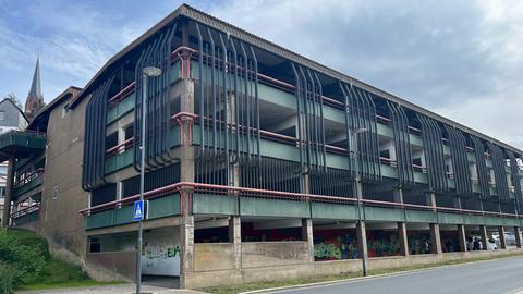 Das Parkhaus aus den 1970er Jahren in Frankenberg. Über dem Erdgeschoss sind weitere drei Etagen. Rote und schwarze Rohre bilden Stilelemente an der Außenfassade.