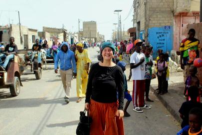 Charlotte steht auf einer Straße im Senegal - im Hintergrund Pferdekutschen. 