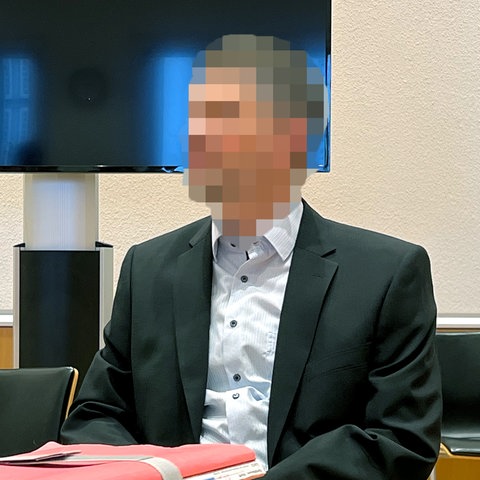 Angeklagter im Gerichtssaal, sein Gesicht ist verpixelt.