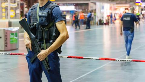 Polizist mit Gewehr vor Absperrung im Bahnhof