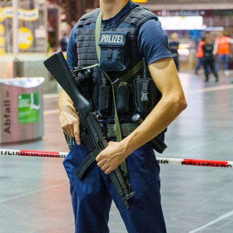 Polizist mit Gewehr vor Absperrung im Bahnhof