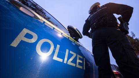 Eine Polizistin steht neben einem Polizeifahrzeug