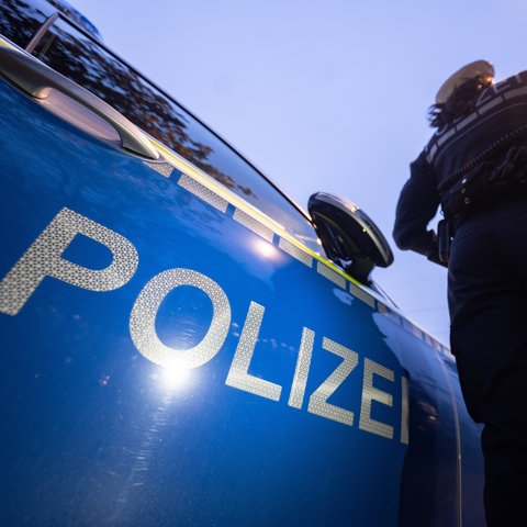 Eine Polizistin steht neben einem Polizeifahrzeug