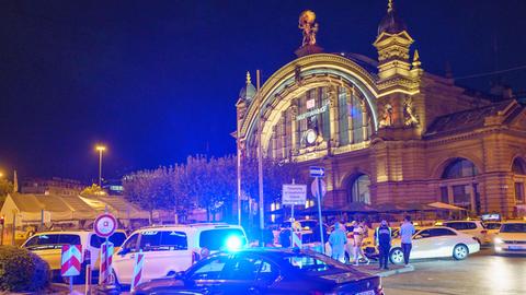 Frankfurter Hauptbahnhof von außen. Es ist dunkel, vor dem Gebäude stehen mehrere Fahrzeuge, darunter auch Polizeifahrzeuge.