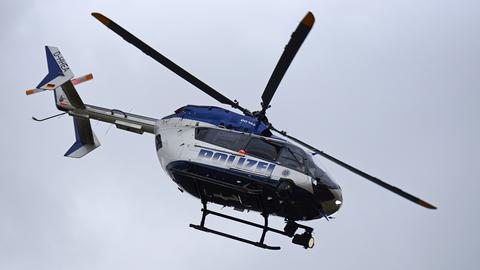 blau-weißer Hubschrauber der hessischen Polizei in der Luft mit sich drehenden Rotorblättern