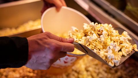  Ein Mitarbeiter füllt einen Eimer mit Popcorn.