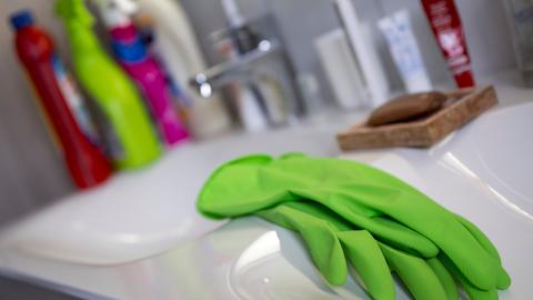 Grüne Gummihandschuhe liegen auf einem Badezimmerwaschbecken