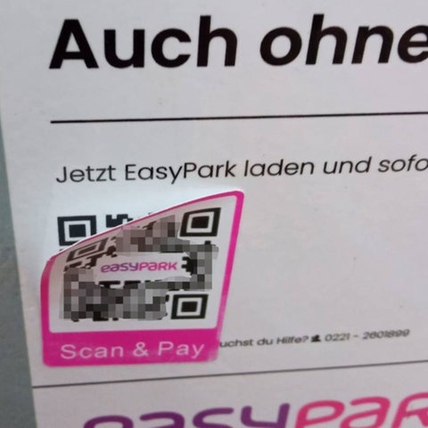 Auf einem Parkautomat klebt ein gefälschter QR-Code