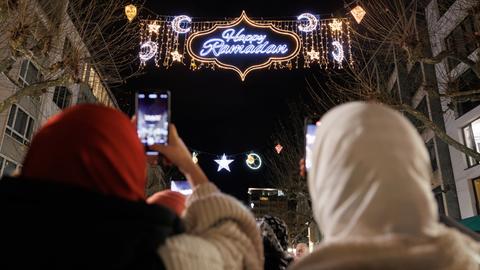 Passanten fotografieren mit ihren Handys die "Happy Ramadan"-Beleuchtung in der Freßgass von Frankfurt