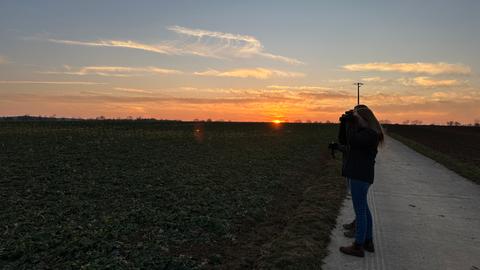 Auf einem Acker in Langgöns suchen Clara Guckenbiehl (links) und Annika Werner (rechts) kurz vor dem Sonnenuntergang mit einem Fernglas nach Rebhühnern.