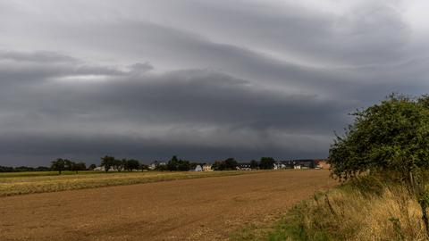 Dunkle Wolken einer aufziehenden Gewitterfront sind über den Feldern zu sehen.